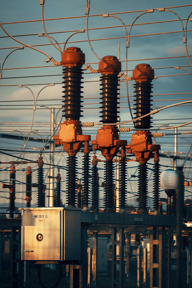 Subestación eléctrica con aisladores de alta tensión y gabinete metálico